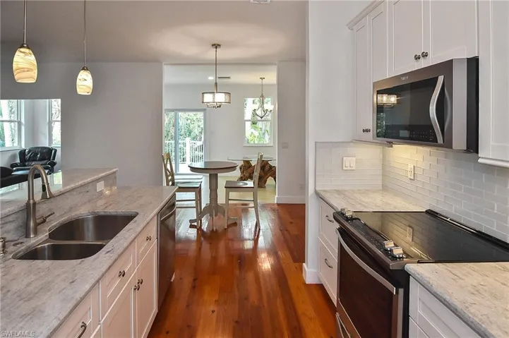 Kitchen with white cabinets, pendant lighting, appliances with stainless steel finishes, and sink