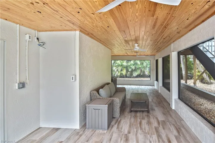 Unfurnished sunroom featuring ceiling fan, wood ceiling, and a wealth of natural light