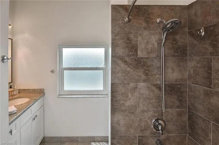 Bathroom featuring tile patterned floors, tiled shower / bath, and vanity