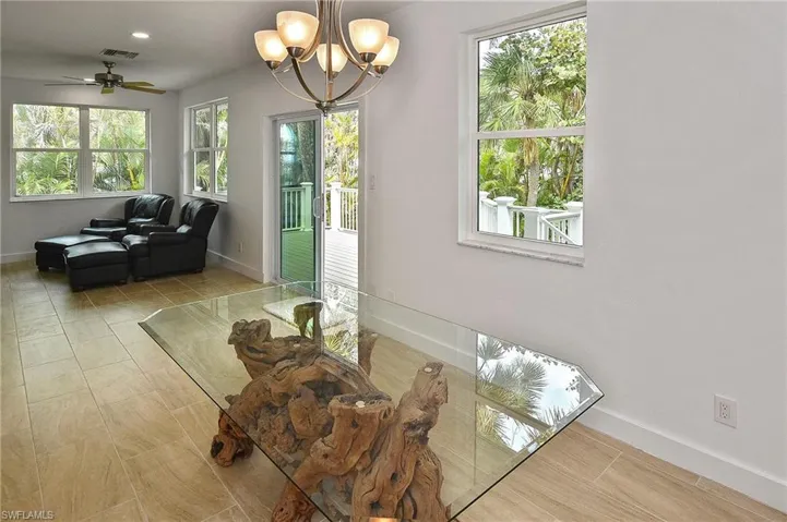 Tiled dining room with ceiling fan with notable chandelier