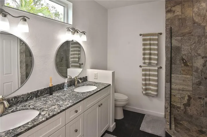 Bathroom featuring a shower, toilet, vanity, and tile patterned flooring
