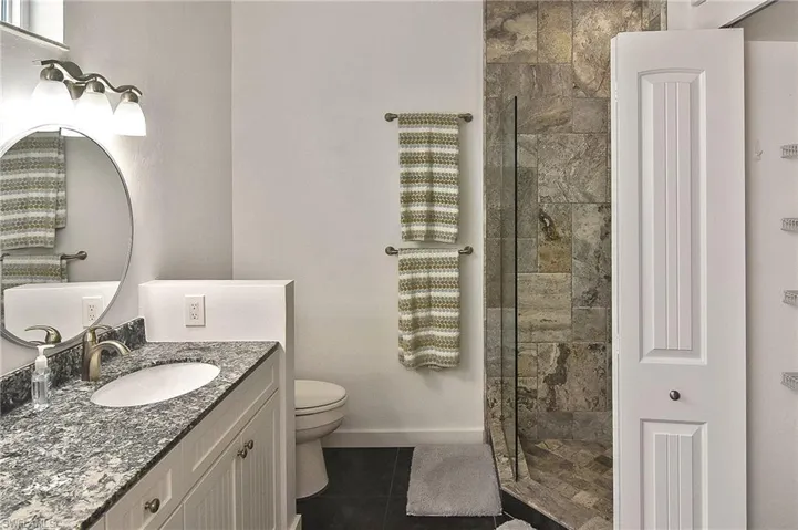 Bathroom featuring toilet, a tile shower, tile patterned floors, and vanity