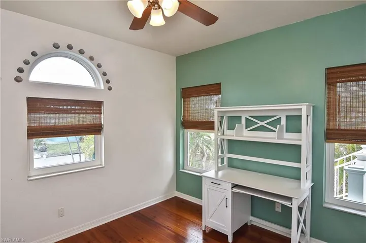 Unfurnished office with ceiling fan, dark hardwood / wood-style floors, and plenty of natural light