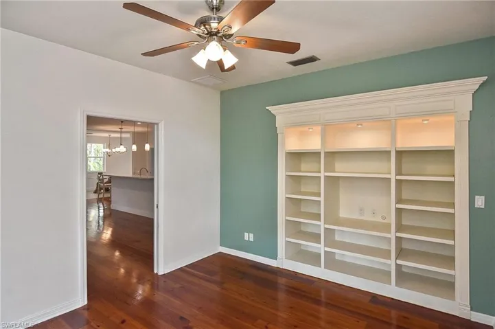 Spare room with dark hardwood / wood-style flooring and ceiling fan with notable chandelier