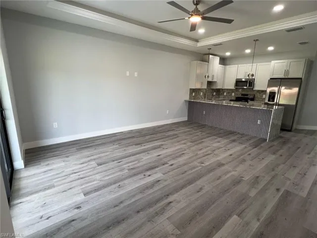Kitchen featuring a raised ceiling, a peninsula, tasteful backsplash, appliances with stainless steel finishes, and ceiling fan