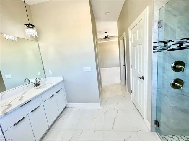 Bathroom featuring light marble finish flooring, a stall shower, and vanity