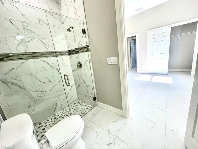 Full bath featuring light marble finish floors and a marble finish shower