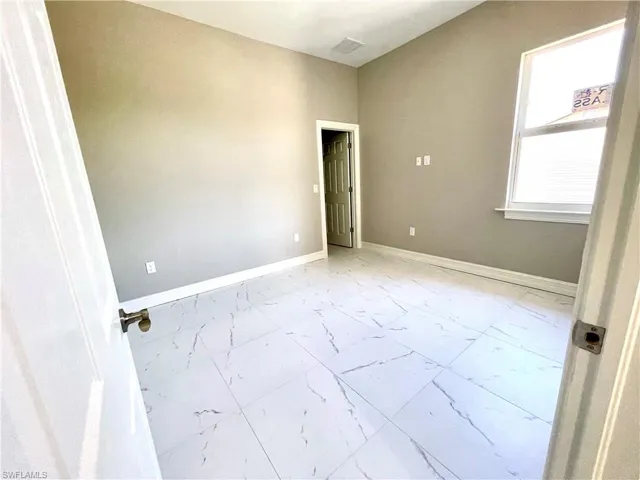 Empty room featuring light marble finish flooring and baseboards
