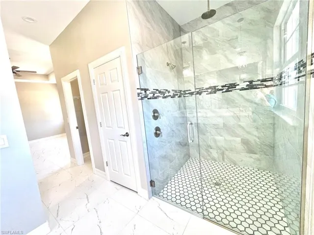 Full bathroom with light marble finish flooring, a shower stall, and ceiling fan