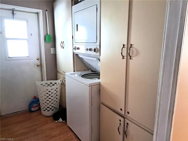 Laundry room with stacked washer / dryer and light hardwood / wood-style flooring