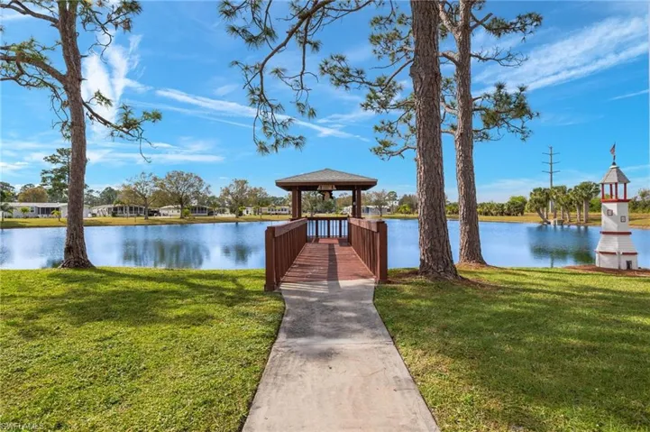 View of dock with a gazebo, a lawn, and a water view