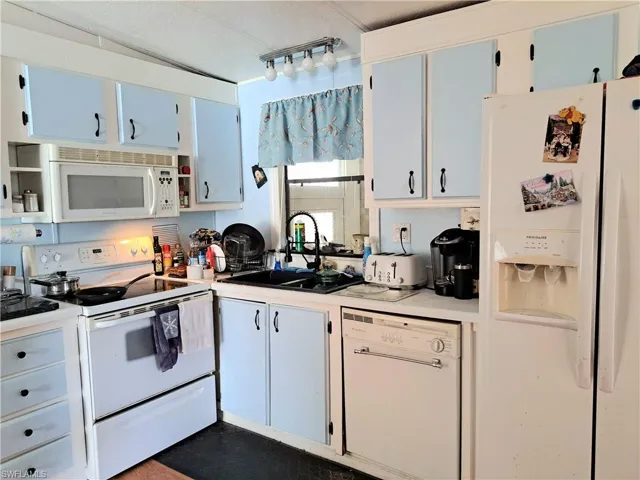 Kitchen featuring white cabinetry, sink, white appliances, and track lighting