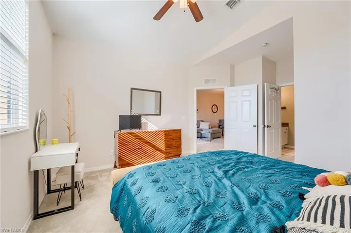 Bedroom featuring ceiling fan, light colored carpet, and vaulted ceiling