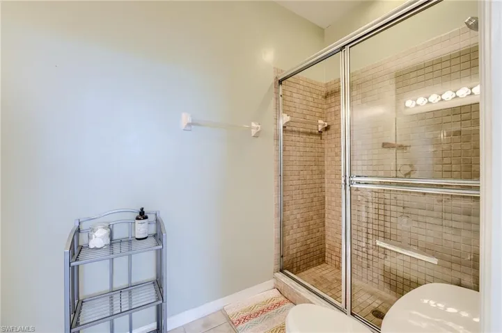 Bathroom with tile patterned floors, toilet, and a shower with shower door