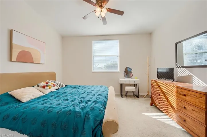 Carpeted bedroom featuring ceiling fan