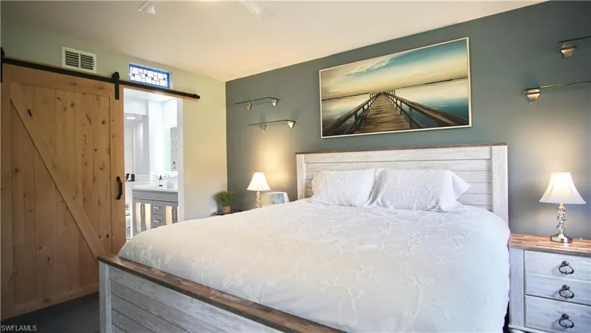 Bedroom with a barn door, carpet, connected bathroom, and ceiling fan