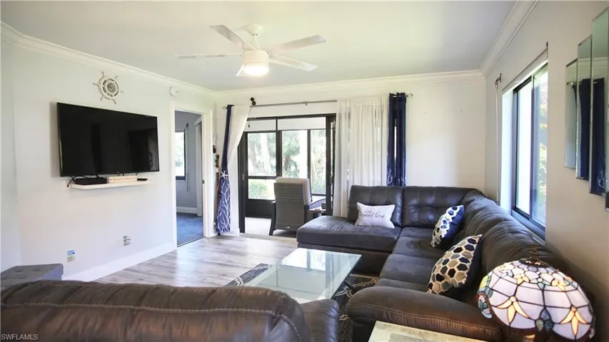 Living room with wood-type flooring, ornamental molding, and ceiling fan
