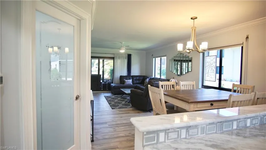 Dining room featuring ornamental molding, ceiling fan with notable chandelier, and light wood-type flooring