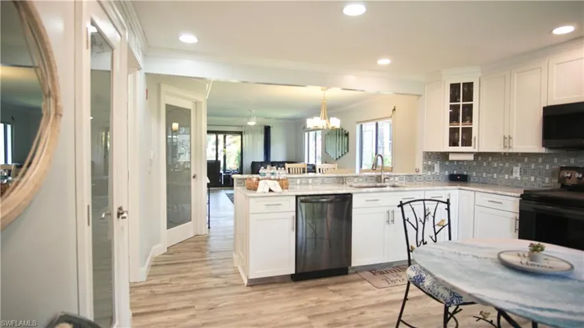 Kitchen featuring kitchen peninsula, dishwasher, light wood-type flooring, sink, and black range with electric cooktop