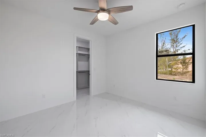 Unfurnished bedroom featuring a walk in closet, a closet, and ceiling fan