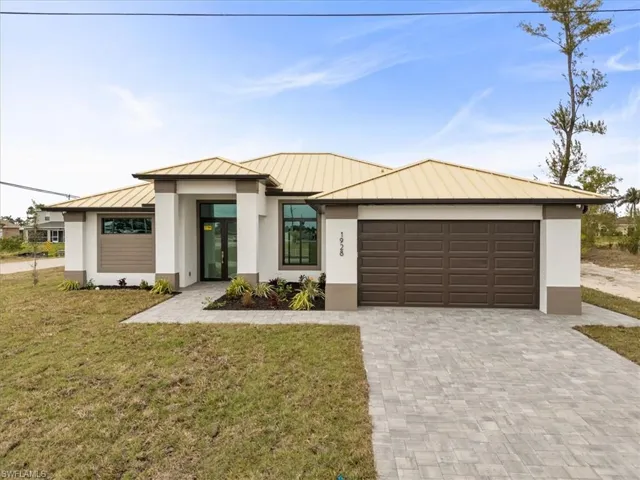 View of front of property with a garage and a front lawn