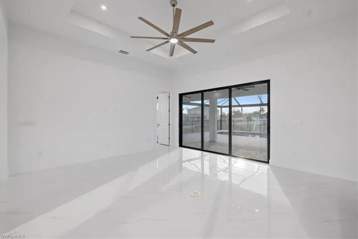 Empty room with ceiling fan, a raised ceiling, and a towering ceiling
