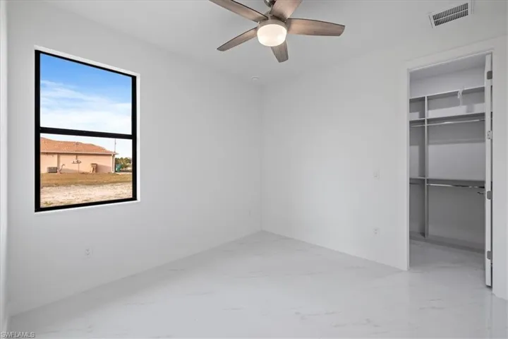 Unfurnished bedroom with a spacious closet, ceiling fan, and a closet