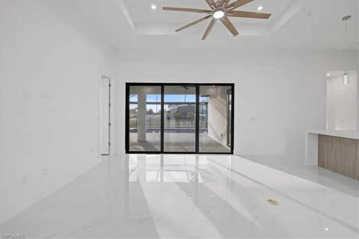 Spare room with a tray ceiling, ceiling fan, and a high ceiling