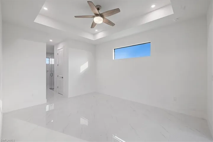 Unfurnished room featuring ceiling fan and a raised ceiling