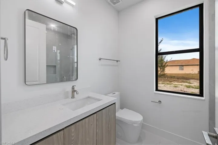 Bathroom with a shower with door, vanity, and toilet
