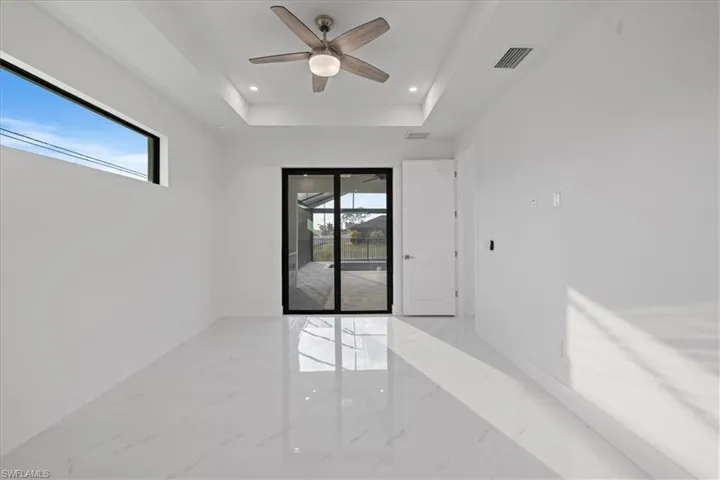 Spare room featuring ceiling fan, a healthy amount of sunlight, and a tray ceiling
