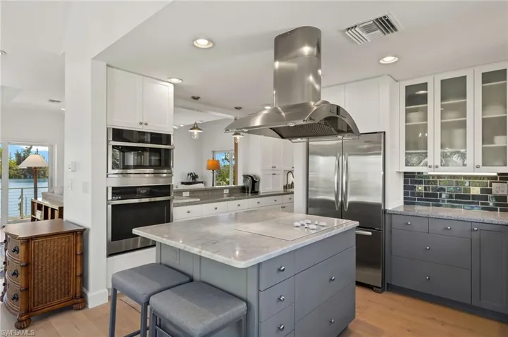 Kitchen featuring gray cabinetry, island range hood, light stone countertops, white cabinets, and recessed lighting