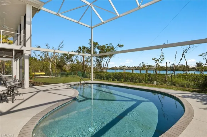 Swimming pool featuring a lanai, a sunroom, a water view, and a patio
