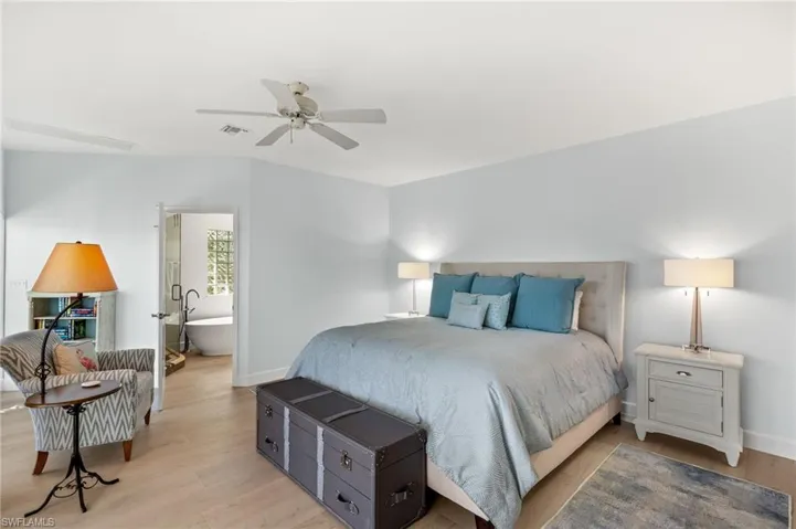 Bedroom with wood finished floors, connected bathroom, and a ceiling fan