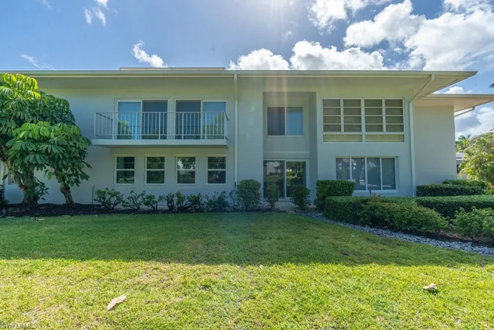 View of front of home with a front yard, stucco siding, and a balcony