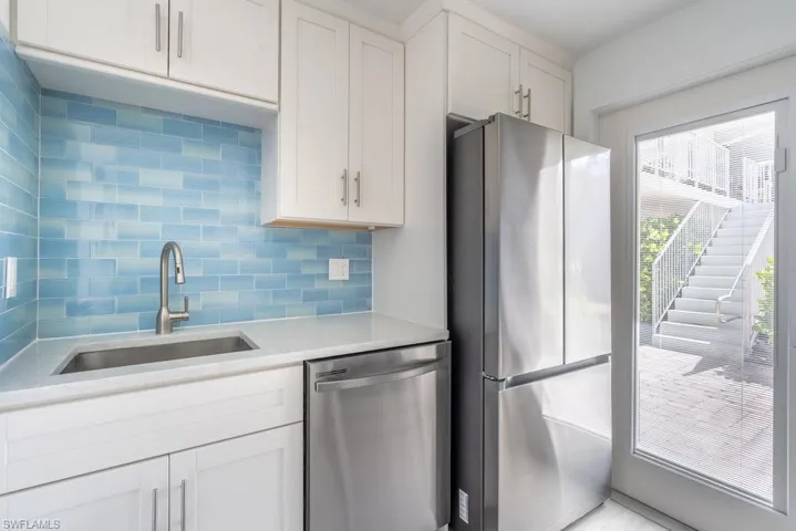 Kitchen featuring appliances with stainless steel finishes, backsplash, light countertops, and white cabinets