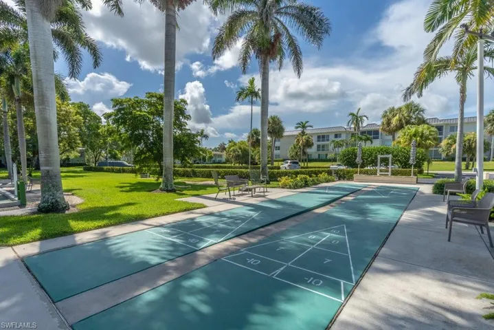 View of home's community featuring a lawn and shuffleboard