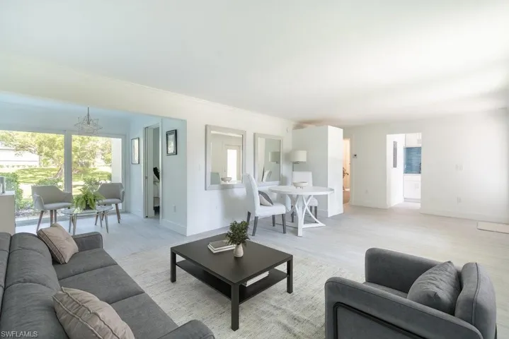 Virtually Staged living area featuring light wood finished floors, a chandelier, and ornamental molding