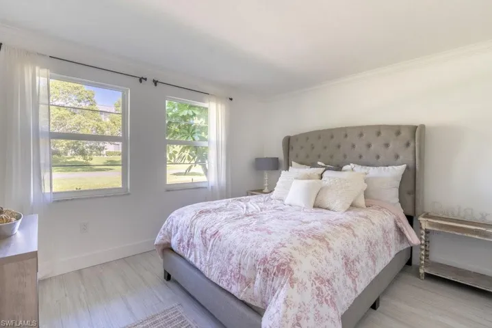 Bedroom with ornamental molding and wood finished floors