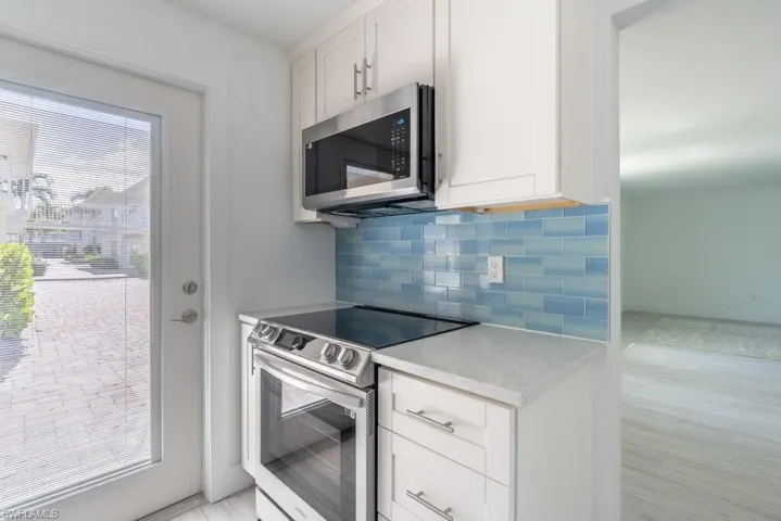 Kitchen featuring stainless steel appliances, backsplash, white cabinetry, and light wood-style floors