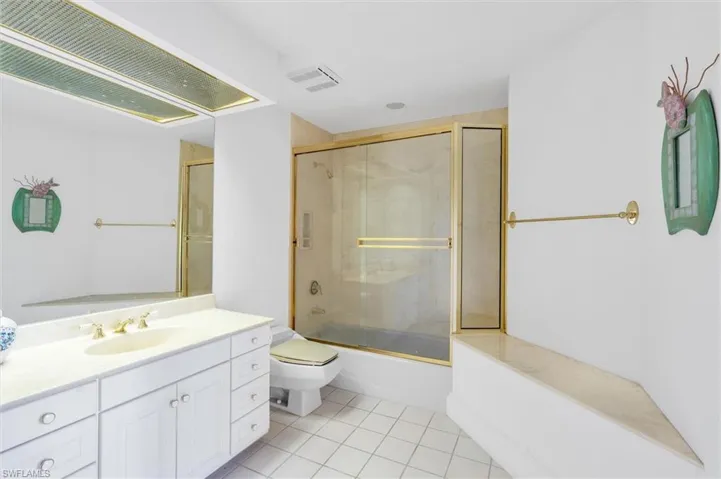Full bathroom featuring toilet, vanity, tile patterned floors, and shower / bath combination with glass door