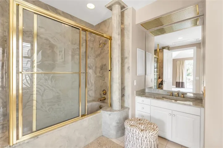 Bathroom with shower / bath combination with glass door, tile patterned floors, and vanity