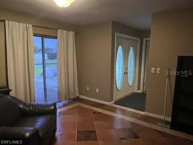 Entrance foyer with inlaid floor details, dark tile patterned floors, and plenty of natural light