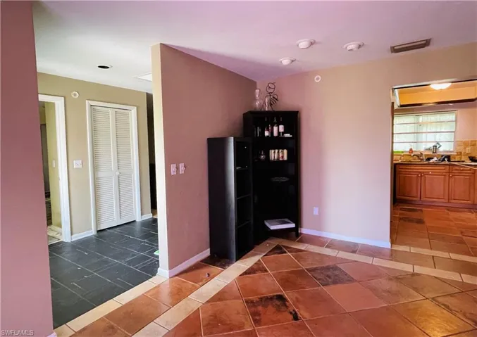 Hall featuring dark tile patterned floors and baseboards