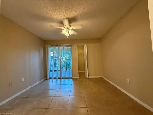 Tiled empty room with a textured ceiling and a ceiling fan