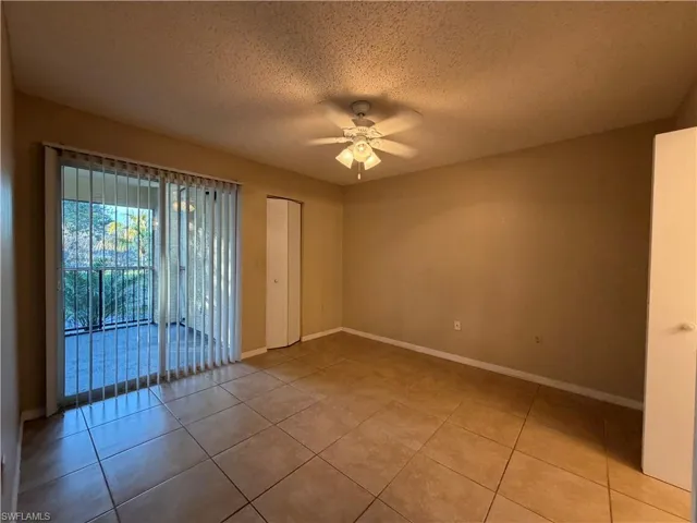 Spare room with a textured ceiling, ceiling fan, and light tile patterned floors