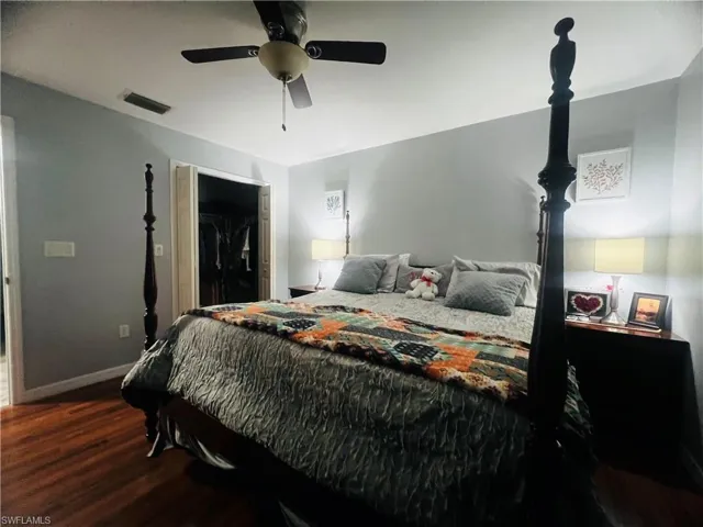 Bedroom featuring dark hardwood / wood-style flooring, a closet, ceiling fan, and a spacious closet