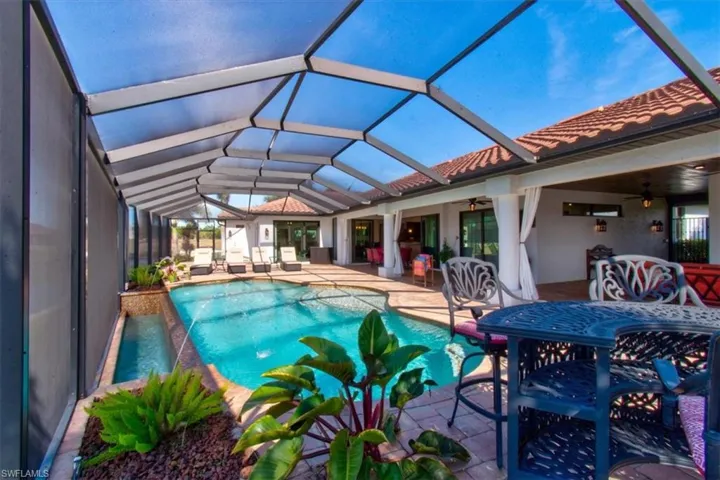 View of swimming pool featuring a patio area, ceiling fan, pool water feature, and glass enclosure