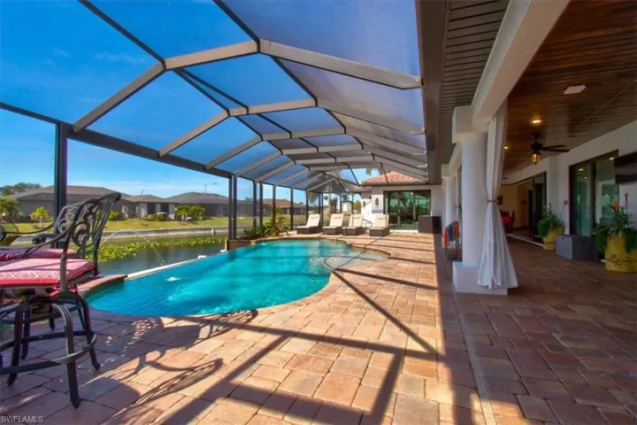 View of swimming pool with a water view, pool water feature, ceiling fan, a lanai, and a patio