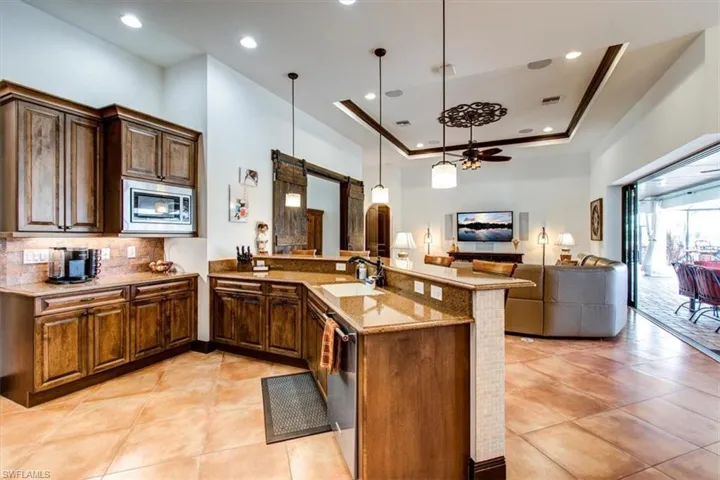 Kitchen with a tray ceiling, kitchen peninsula, pendant lighting, and appliances with stainless steel finishes